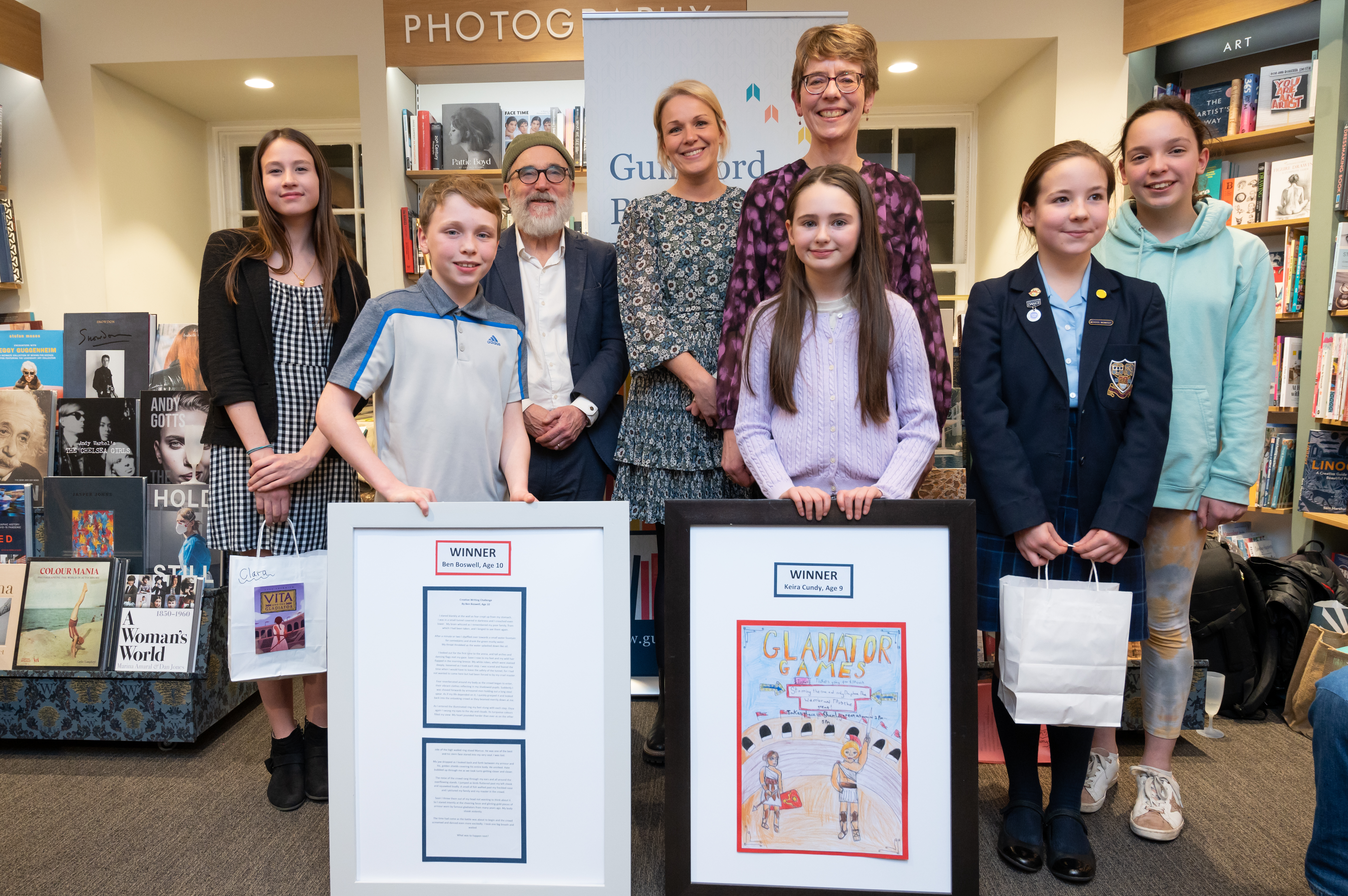 Ally Sherrick author with young shortlistees and winners of the Guildford Book Festival gladiator writing and poster-design competition displaying their entries